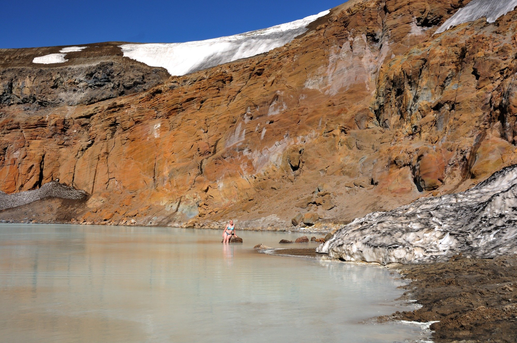 Karin bader i vulkansøen Viti med sne rundt om